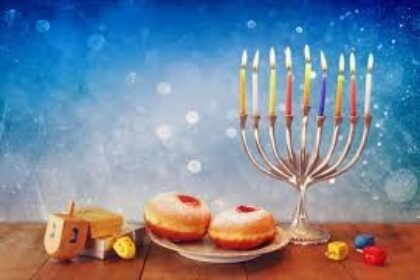 Menorah, donuts, and dreidels on wooden table.