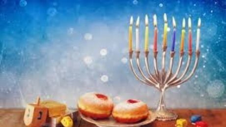 Menorah, donuts, and dreidels on wooden table.