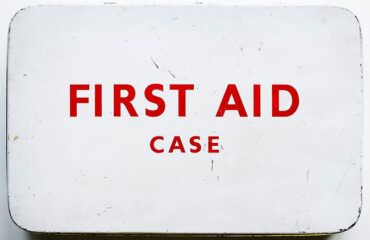 A first aid case sign on the side of a building.